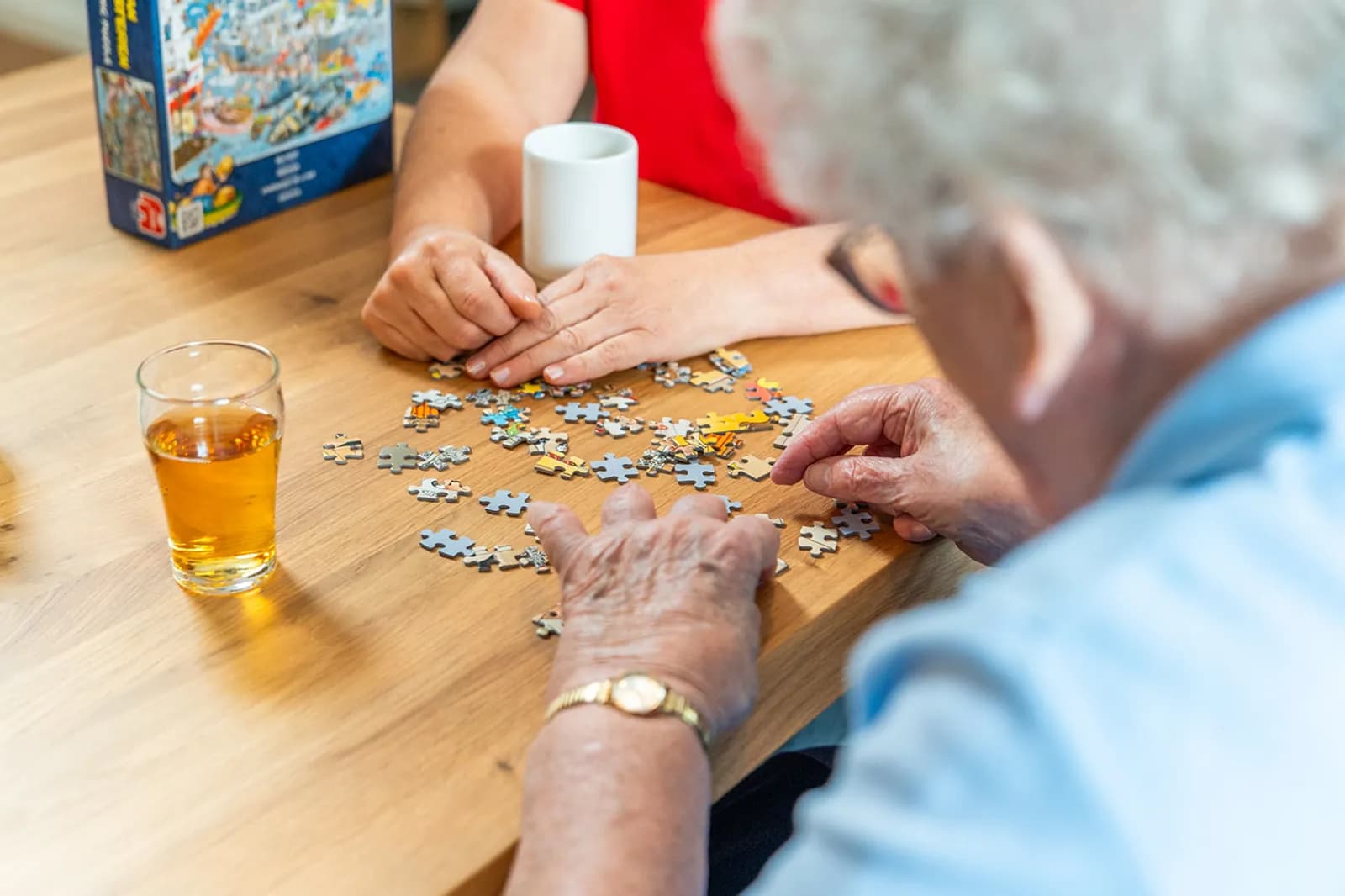 Een zorgmedewerker en een oudere aan het puzzelen