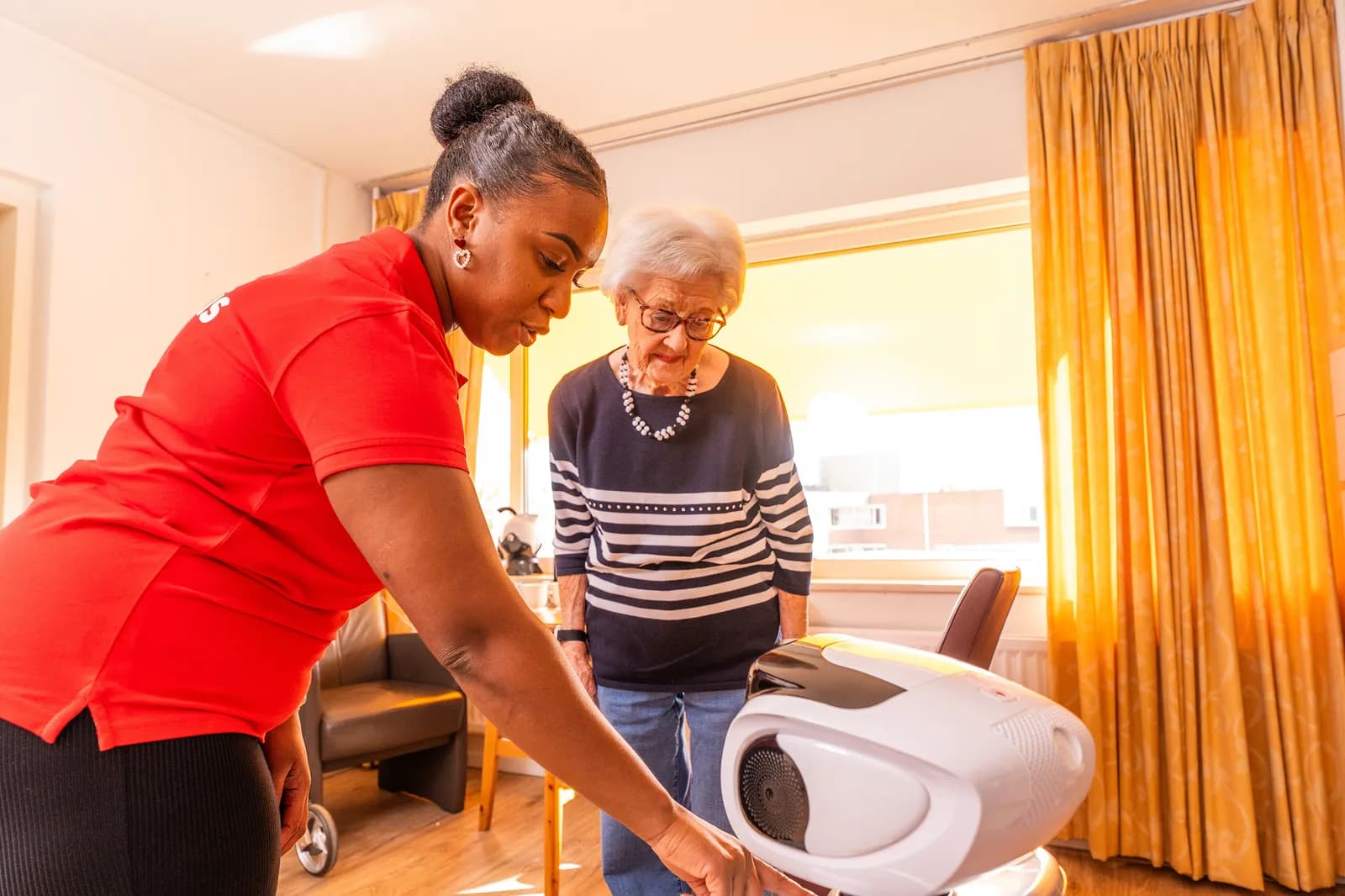 Een zorgmedewerker en een oudere en een zorgrobot
