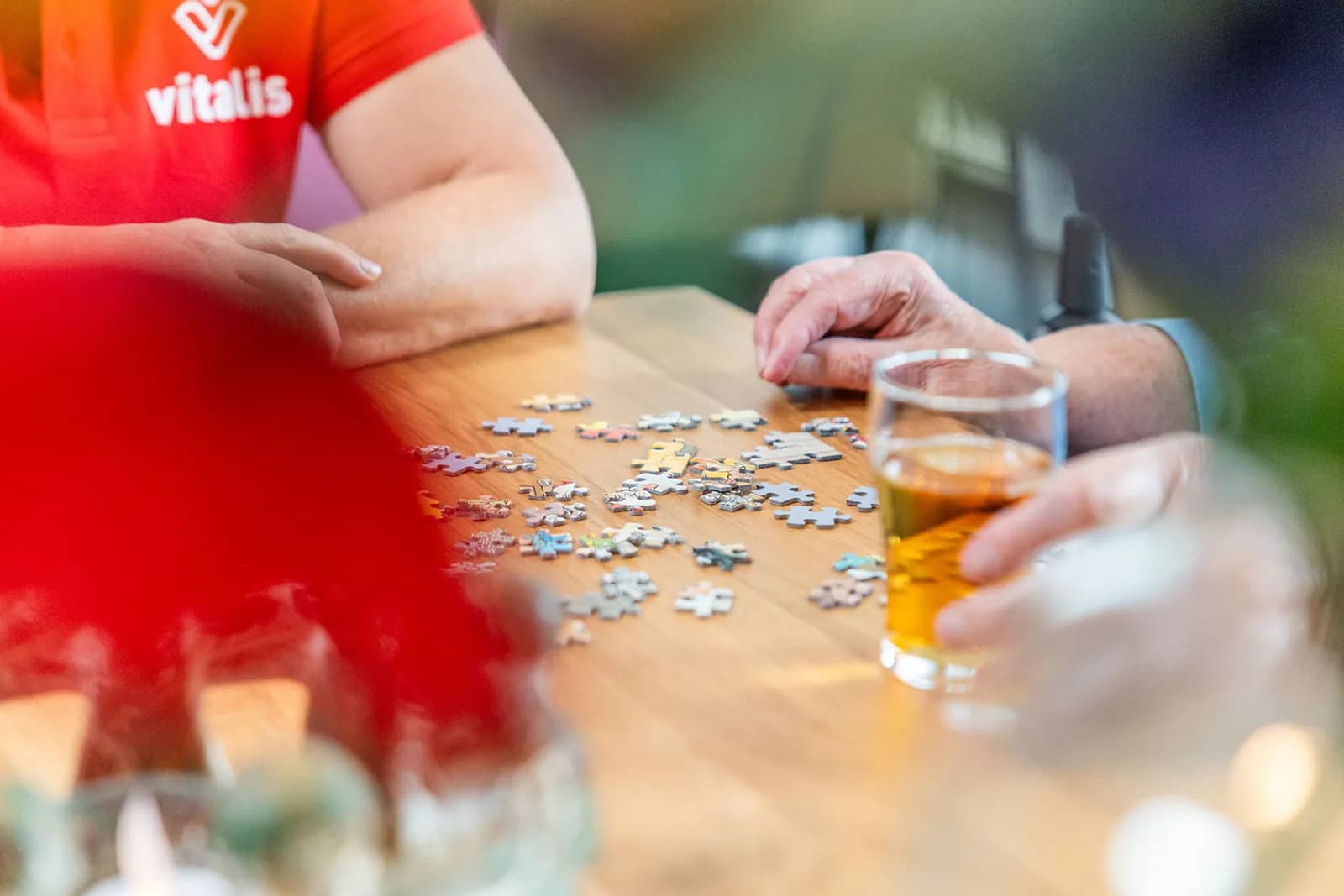 Oudere puzzelt met zorgmedewerker aan tafel met thee