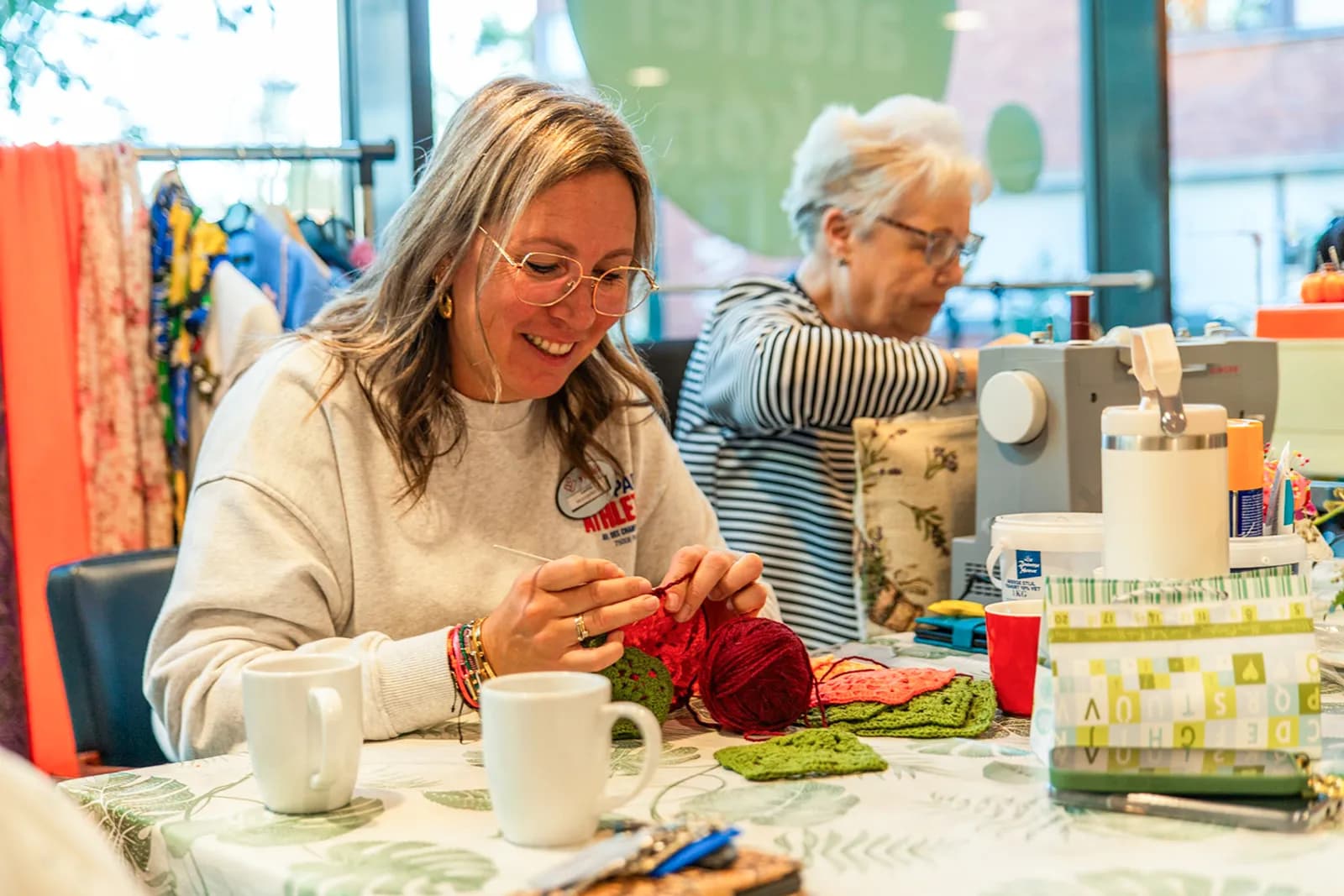 Een zorgmedewerker en een oudere achter het naaimschine