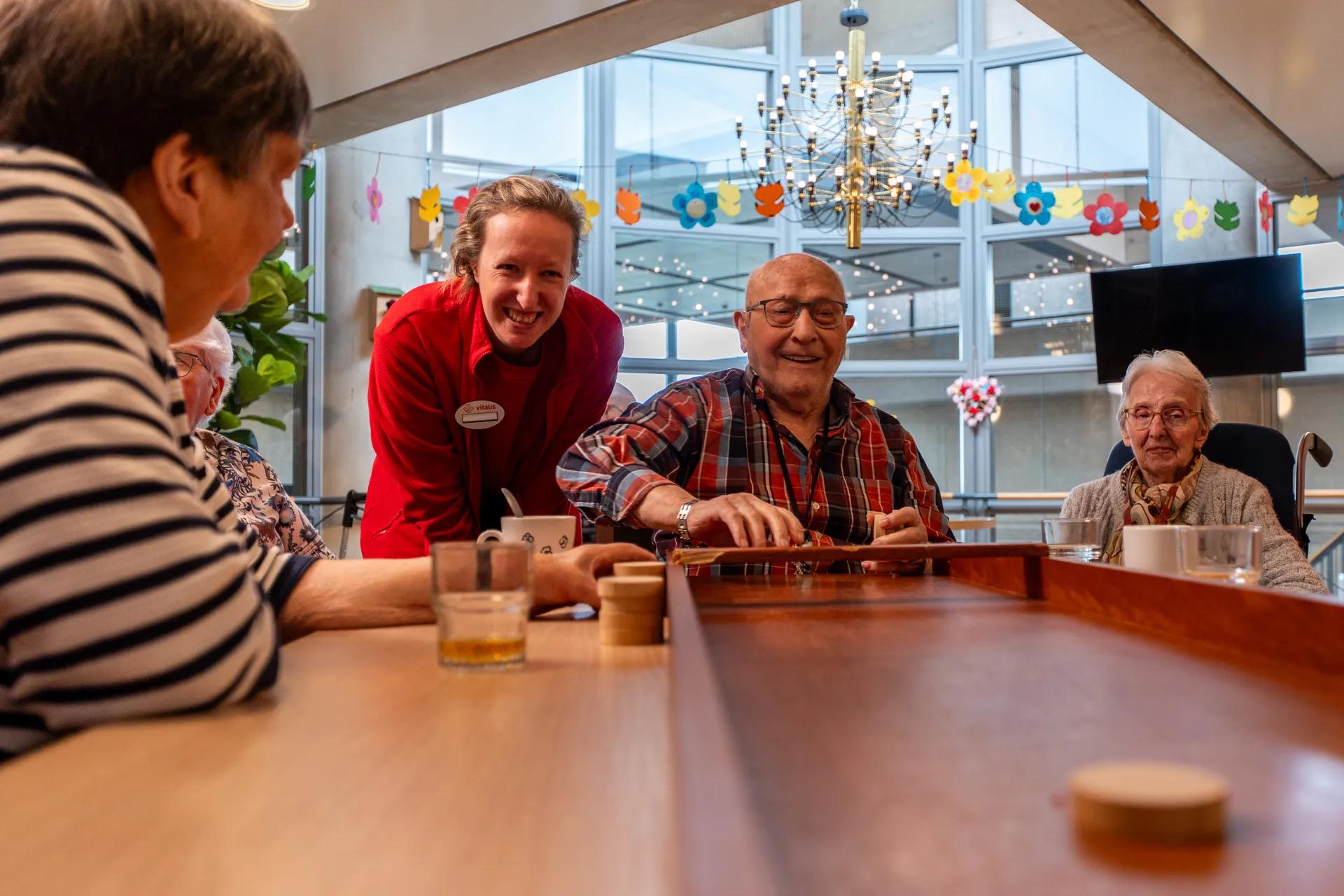 Een medewerker en 3 ouderen zijn aan het sjoelen