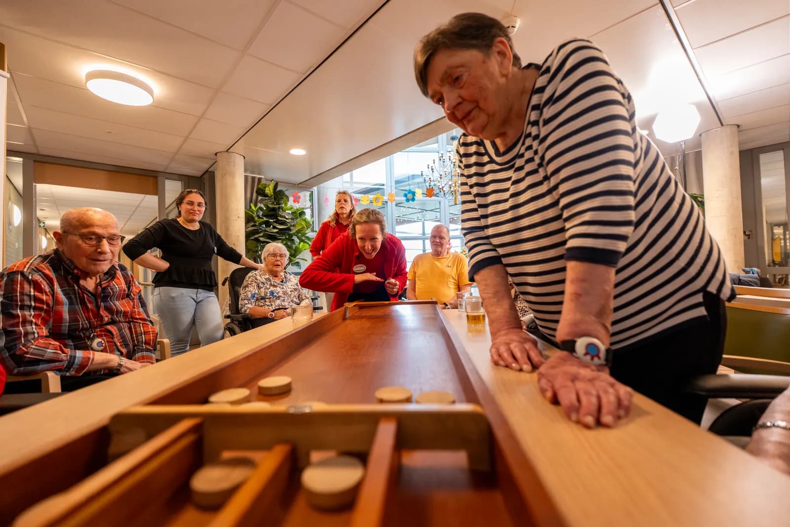 Een medewerker en oudere aan het sjoelen